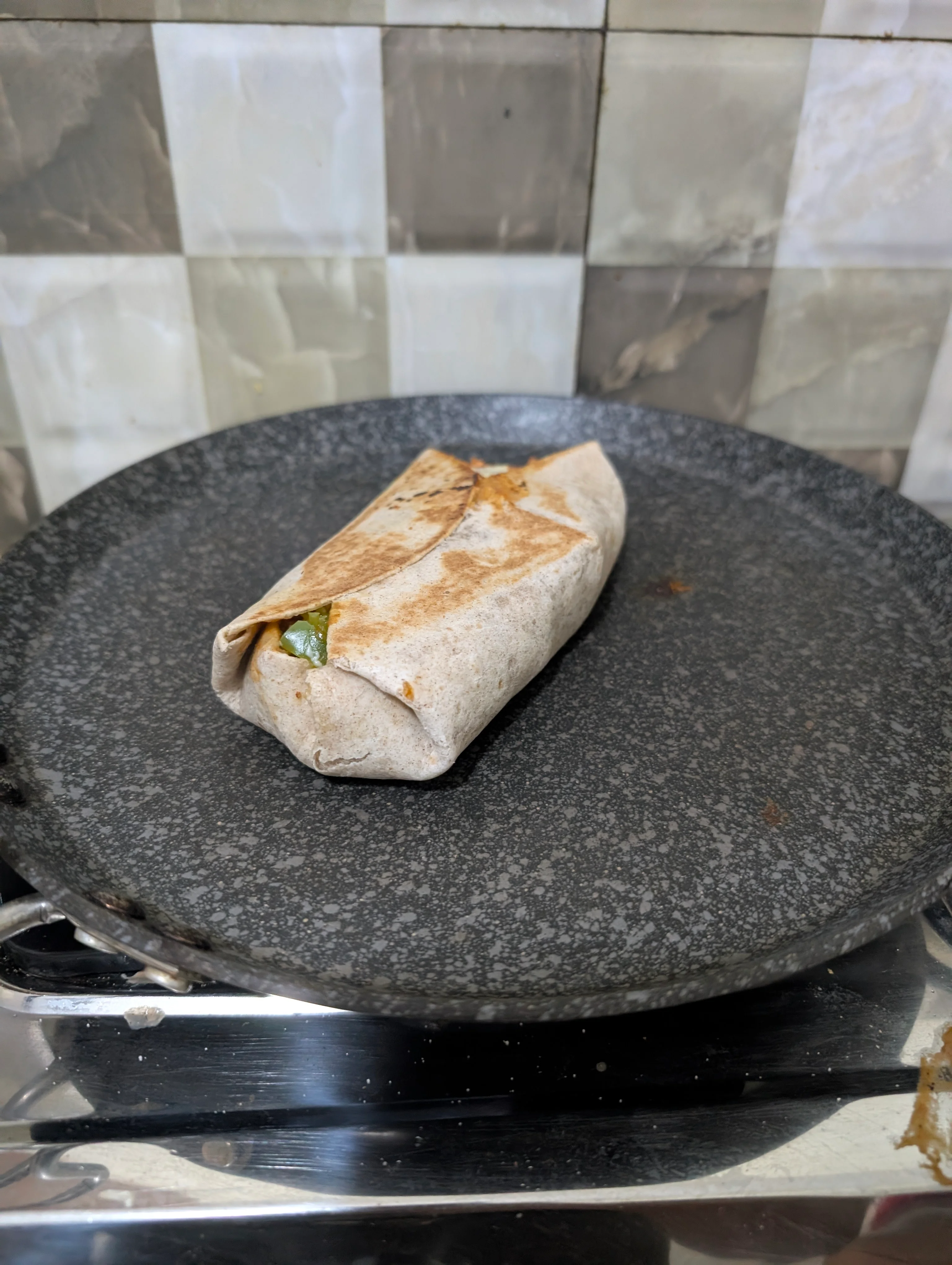 A burrito being lightly grilled on a pan. Shocking it has not split open its guts all over the place.