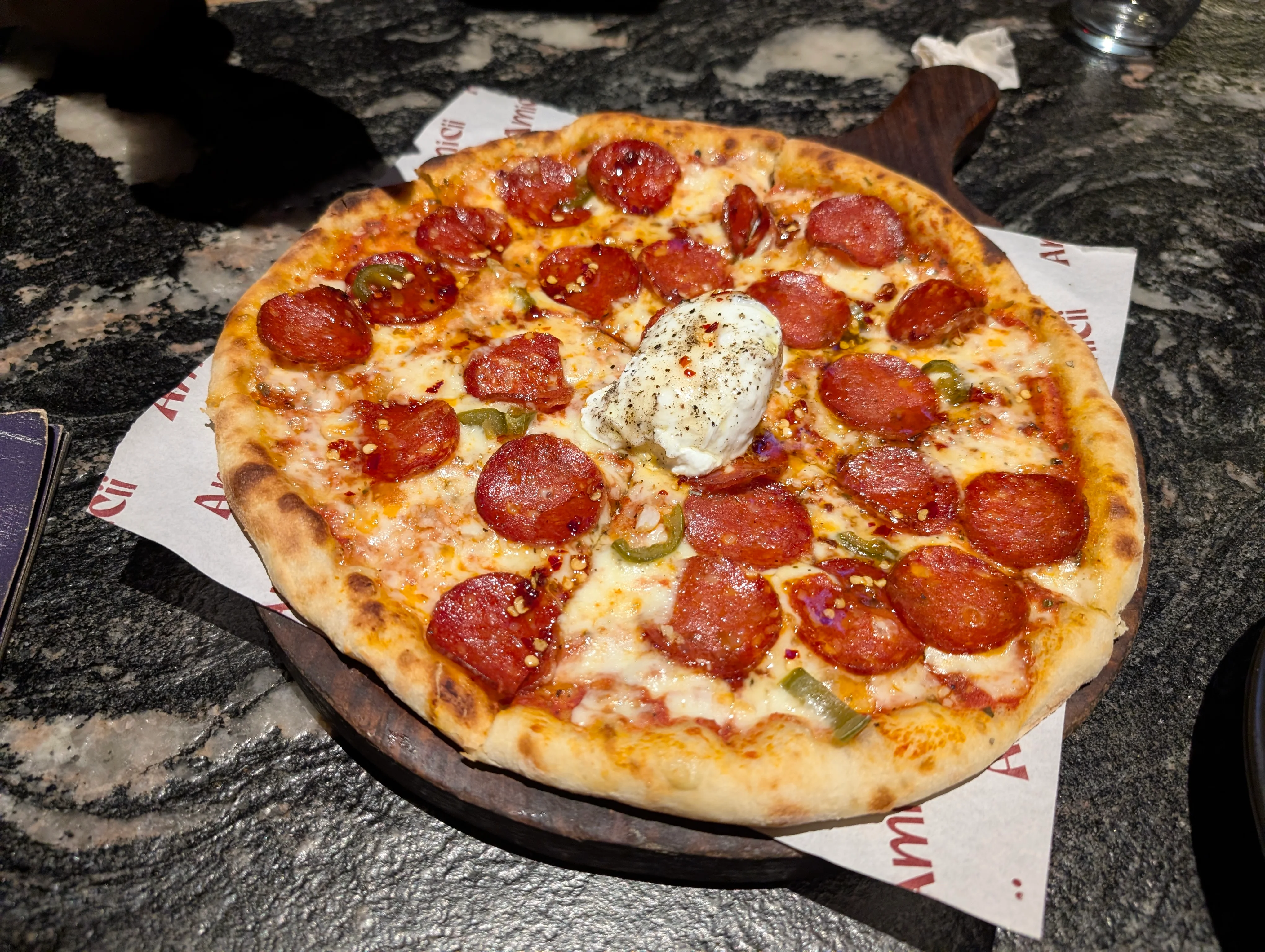 A regular pepperoni pizza with a ball of burrata cheese in the middle.