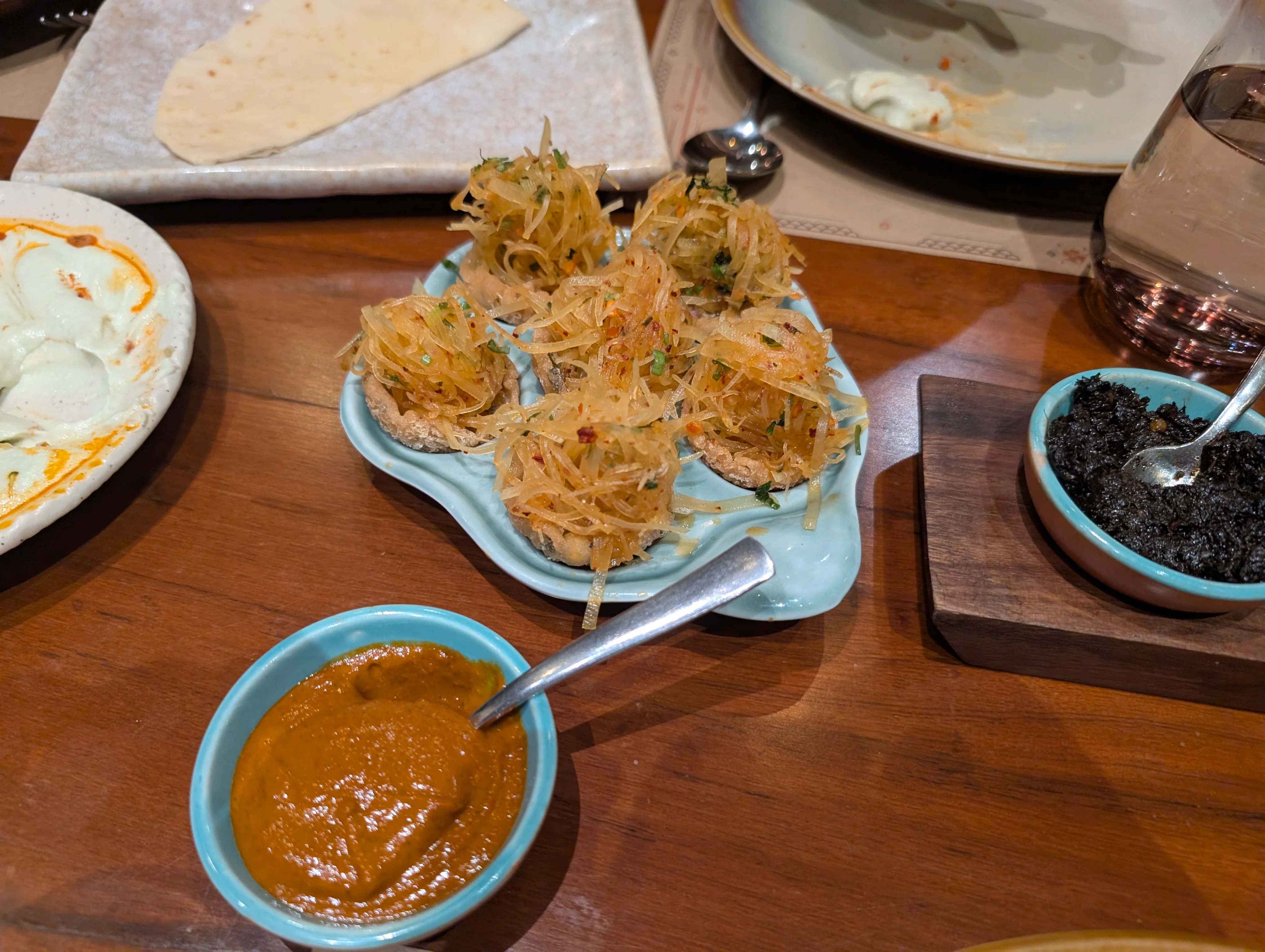 A plate of small poppers that have a pile of cured papaya shreds on top.